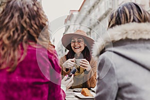 Three women friends having coffee in a terrace in Oporto, Portugal. Having a fun conversation. Lifestyle, tourism and holidays