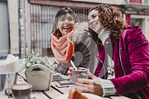 Three women friends having coffee in a terrace in Oporto, Portugal. Having a fun conversation. Lifestyle, tourism and holidays