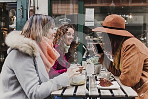 Three women friends having coffee in a terrace in Oporto, Portugal. Having a fun conversation. Lifestyle, tourism and holidays