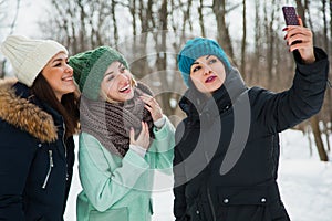 Three women friends outdoors in knitted hats on a snowy cold winter weather.