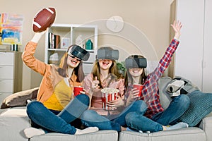 Three women in modern virtual reality headsets having expirience in watching football match at home. Girls in vr glasses