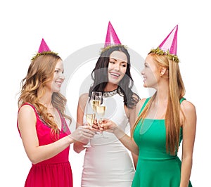 Three women in pink hats with champagne glasses