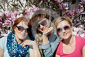 Three women posing with blooming magnolia