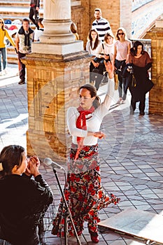 Three women in traditional costumes dance spanish flamenco on the plaza de Espana on February 2019 in Seville