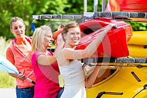 Three women unloading kayak from boat trailer