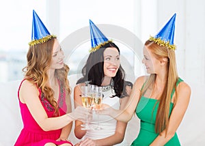 Three women wearing hats with champagne glasses