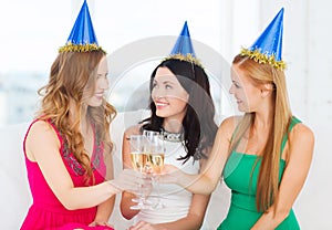 Three women wearing hats with champagne glasses