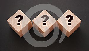 Three wooden blocks with black question marks. Faq questions and answers concept. Educaion or business project concept
