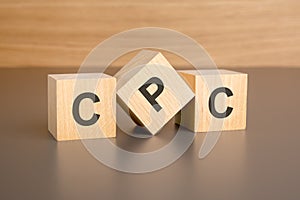 three wooden blocks on a brown background, with the abbreviation CPC - Cost Per Click