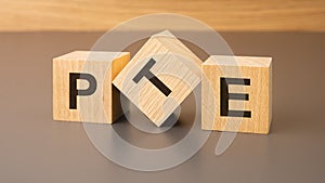 three wooden blocks on a brown background, with the abbreviation PTE - Pearson Tests of English
