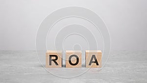 three wooden blocks with the letters ROA on the gray table. business concept