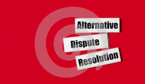 Three wooden blocks with the text ADR Alternative Dispute Resolution on a bright red background. Copy space