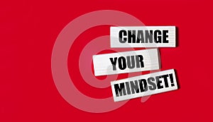 Three wooden blocks with the text CHANGE YOUR MINDSET on a bright red background. Copy space