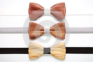 Three wooden bow ties with white, grey and black ribbons. Flat lay, isolated. Team work, career, wedding, eco concept.