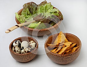 Three wooden bowls with fresh green salad, quail e