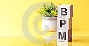 Three wooden cubes with letters - bpm - BUSINESS PROCESS MANAGEMENT, on blue table, space for text in right. Front view concepts,