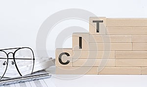 Three wooden cubes with letters CIT on the white table with keyboard and glasses photo