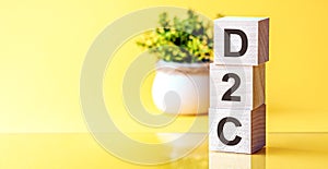Three wooden cubes with letters - D2C - DTC Advertising Direct-to-Consumer, on blue table, space for text in right. Front view