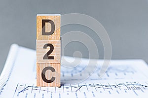 Three wooden cubes with letters - D2C - DTC Advertising Direct-to-Consumer, on blue table, space for text in right. Front view