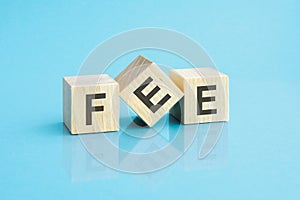 three wooden cubes with the letters FEE on the bright surface of a blue table