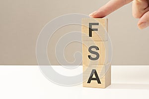 three wooden cubes with the letters FSA on the bright surface of a white table