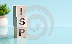 Three wooden cubes with letters ISP - Internet Service Provider, on blue table, more in background, space for text in right