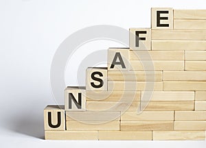 Three wooden cubes with letters UNSAFE on the white table