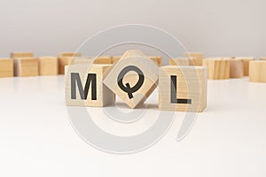 three wooden cubes with MQL symbols on them. white background. in the background there are many wooden blocks of photo