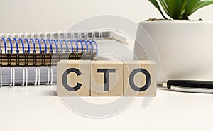 three wooden cubes with word cto on white stone like board, view from above