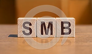 Three wooden cubes with word SMB - short for Server Message Block - lying on the table on orange background