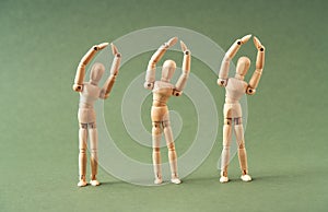 Three wooden figures exercising in a synchronized way