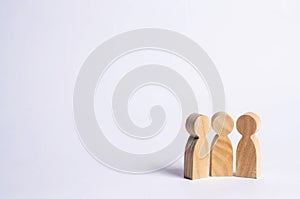 Three wooden figures of people stand together on a white background. Abstraction of a meeting, discussion, conversation. People d