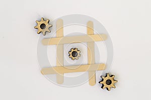 Three wooden gears from the mechanism lie in a row in a line in the game of tic tac toe, in a grid on a white background