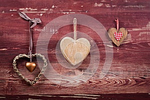 Three wooden hearts on a red board