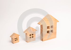 Three wooden houses stand in a row in order of increasing on a white background. The concept of buying and selling real estate. Re