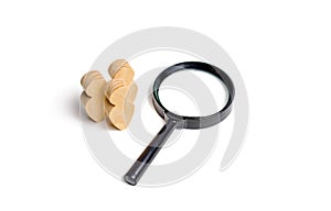 Three wooden human figure stands near a magnifying glass on a white background. The concept of the search for people and workers.