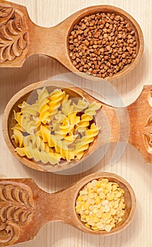 Three wooden spoon with buckwheat, lentil and pasta fusilini