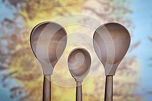 Three wooden spoons on a blue-yellow background close-up