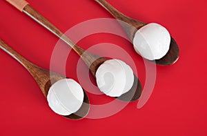 Three wooden spoons with dumplings on the red background