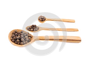 Three wooden spoons with peppercorns