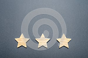 Three wooden stars on a gray background. The concept of quality and prestige. High quality and reliability, universal acceptance