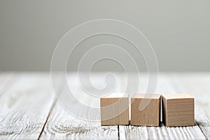 Three wooden toy cubes on grey wooden background