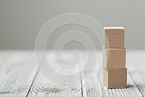 Three wooden toy cubes on grey wooden background