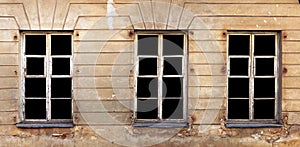 Three wooden white windows in the yellow plastered wall of a