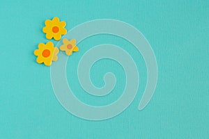 Three Wooden Yellow Craft Flowers on an Aqua Background.