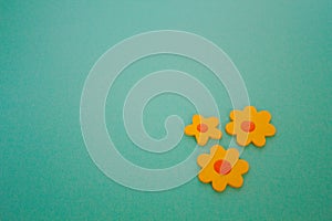 Three Wooden Yellow Craft Flowers on an Aqua Background.