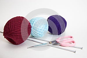 Three wool balls, knitting needles and scissors