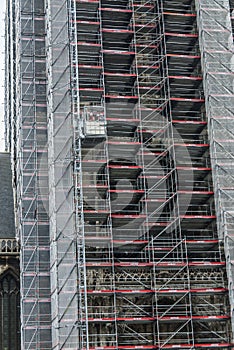 Three workers in a construction lift at scaffolded St-Bavo-cathedral