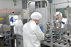Three workers in uniforms at production line in plant photo