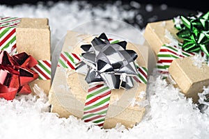 Three wrapped holiday gifts with shiny bows and ribbon sitting o